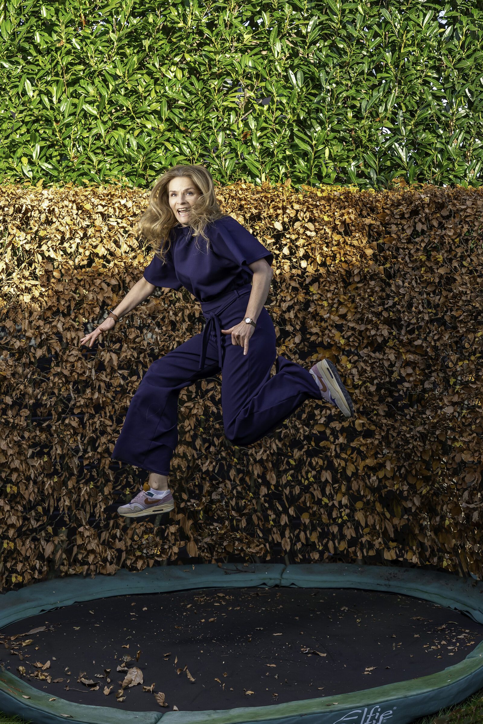 Alja Sluiter springt op een trampoline voor een beukenhaag