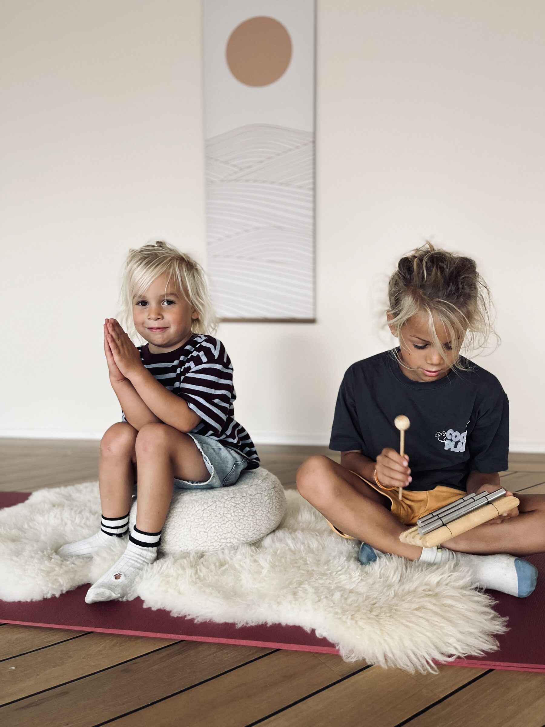 Twee kinderen op een yogamat met een schapenvacht